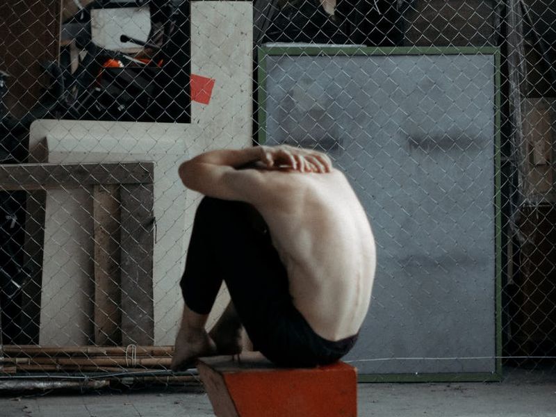 Man performing a controlled bodyweight squat in a minimalist space.